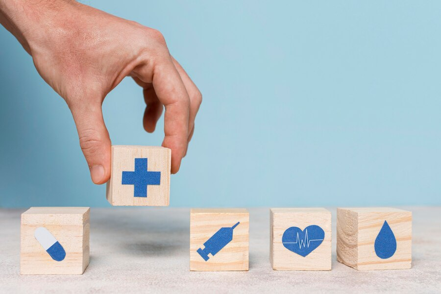 Hand arranging wooden blocks with medical symbols.